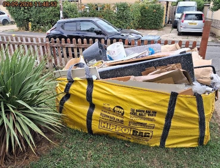 Yellow HIPPO bulk bag packed with builders and bulky waste including timber, cardboard and granite worktop offcuts ready for collection
