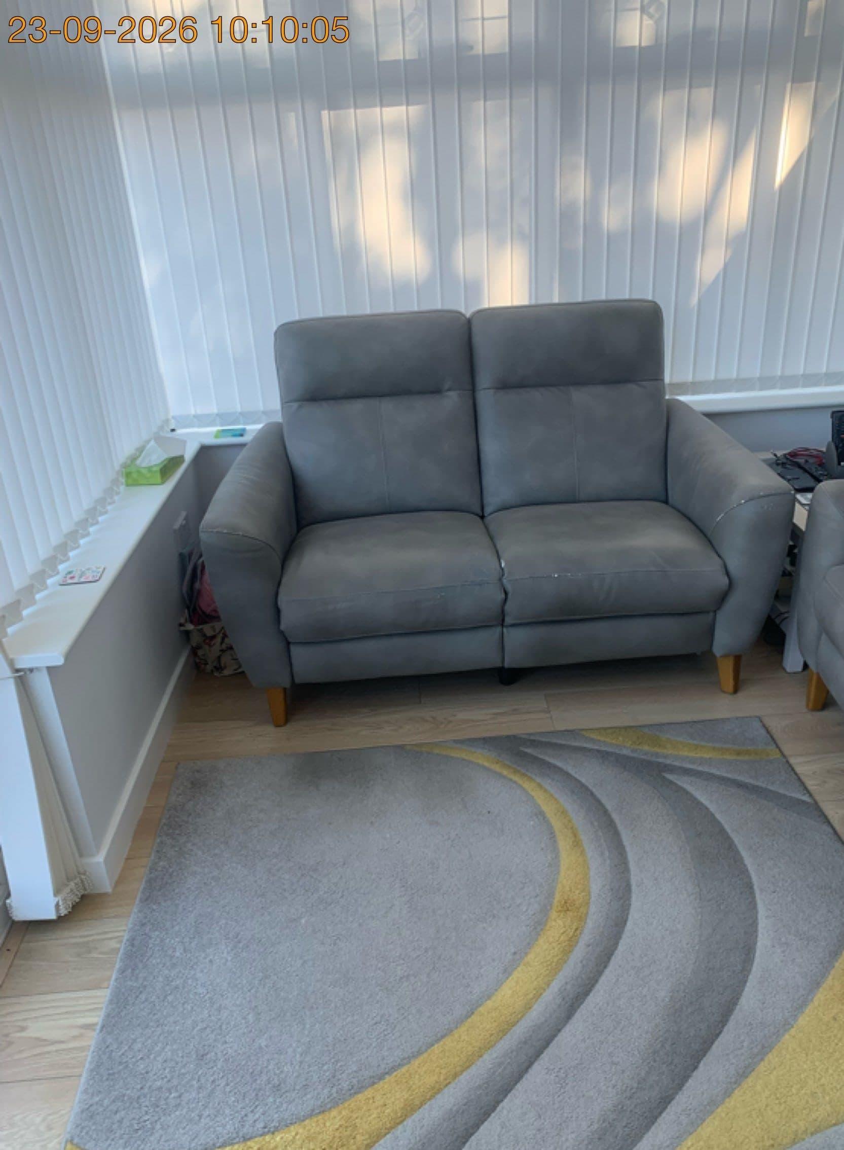 Grey 2-seater recliner sofa in a conservatory on Sussex Road, Bletchley, before removal