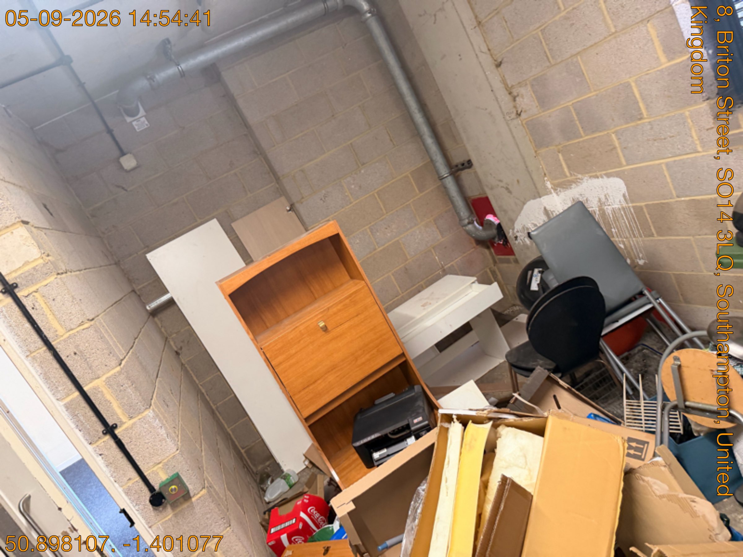 Fly-tipped bureau, office chair, printer and boxes of clutter dumped in a communal bin store before clearance