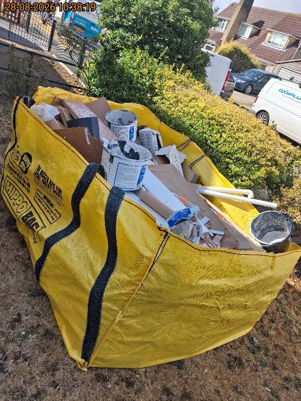 Yellow HIPPO builder’s bag filled with construction and DIY waste including paint tubs, plasterboard and pipes
